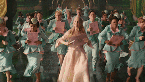 Glinda happily dancing with a group in Wicked